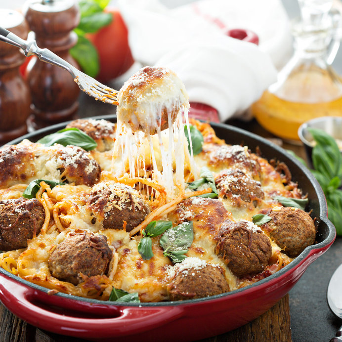 Cheesy spaghetti and meatballs in a red casserole dish